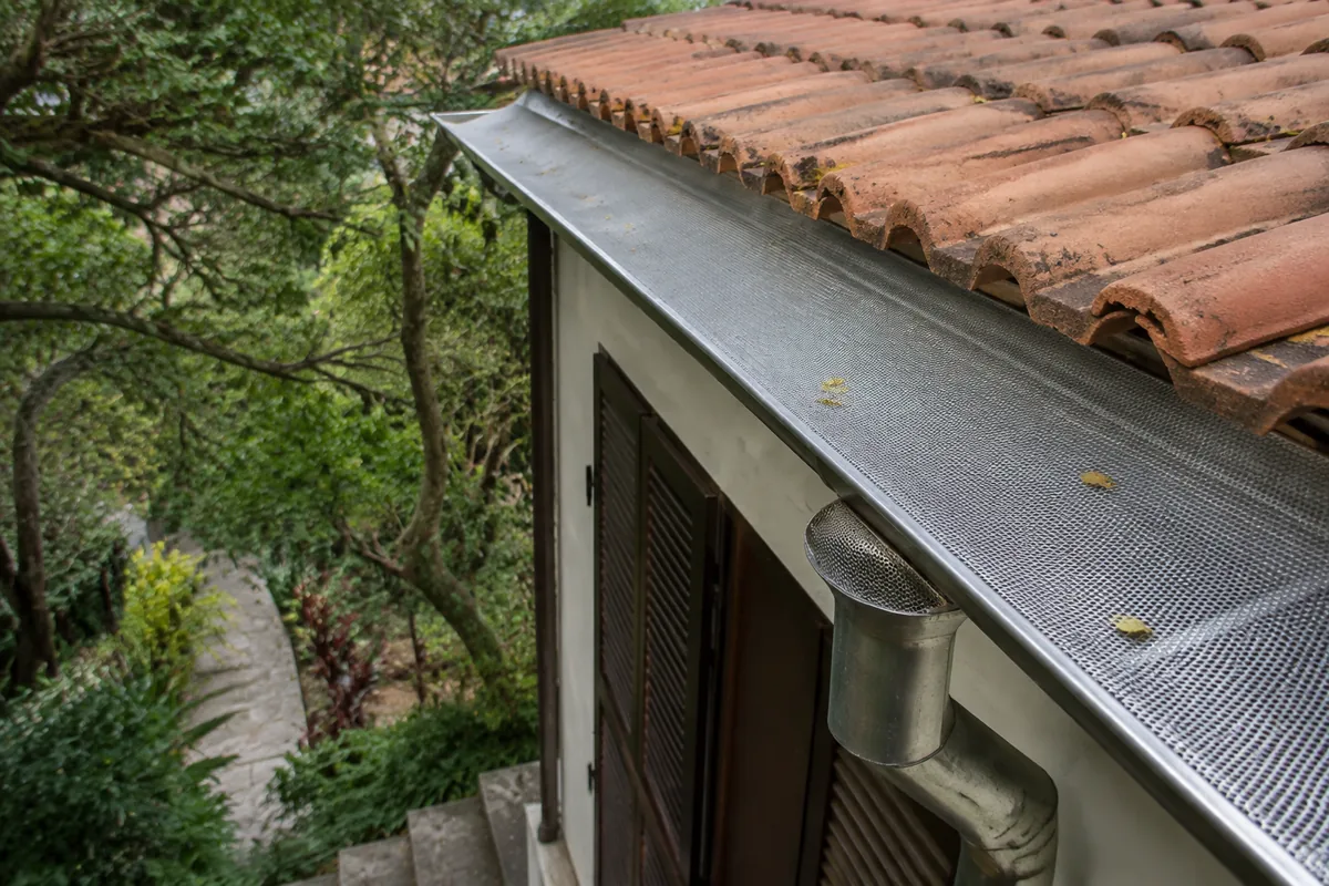 Protetor de folhas instalado em calha de residência arborizada